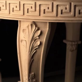 A high-detail close-up of custom wood fabrication showing the precision-carved Greek Key pattern and floral scrollwork on a solid wood table leg and apron.