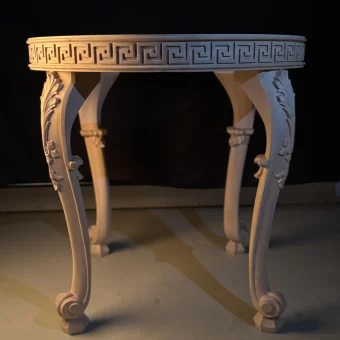 A masterful piece of custom woodwork featuring a round table with a deeply carved "Greek Key" or Versace-inspired apron and elegantly curved legs with acanthus leaf motifs.