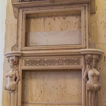 A grand custom-carved wooden fireplace mantel featuring two detailed mermaid sculptures acting as pilasters on either side of the hearth.