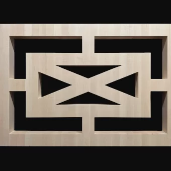 A close-up of a precision-cut solid wood decorative element featuring a geometric "X" or cross design within a rectangular frame, showcasing clean lines and expert joinery.