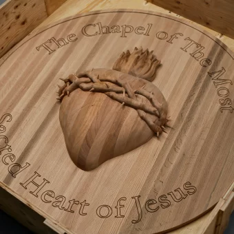 A circular wooden plaque for "The Immaculate Heart of Mary" featuring a 3D carved heart and floral border, representing high-detail custom woodwork.