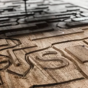 A technical view of an active CNC machine carving complex geometric channels into a wood panel, representing the technology-driven side of custom wood fabrication for custom woodwork.