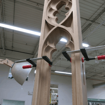 A close-up of Gothic-style window tracery being clamped during assembly, highlighting the structural integrity and detail of professional custom wood fabrication and custom woodwork.