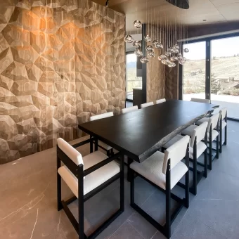 A luxury dining room featuring a floor-to-ceiling accent wall with a deep-relief diamond "G" texture, blending organic stone patterns with modern geometric precision.